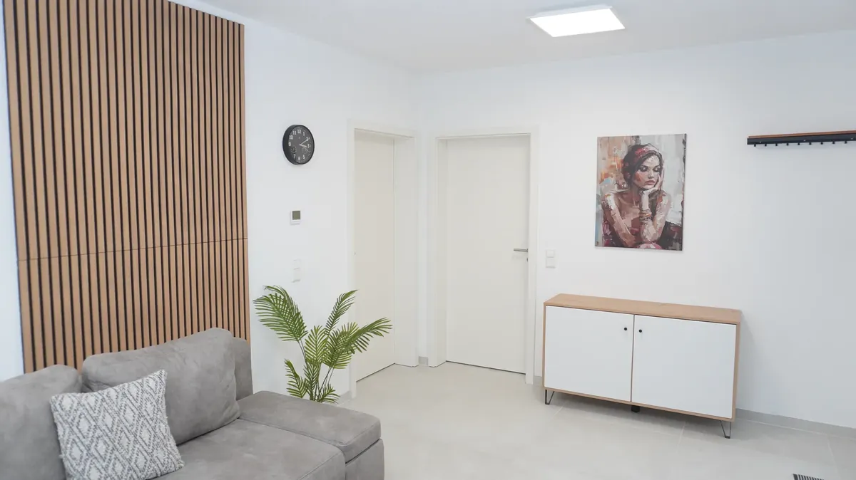 Wohnbereich mit Holzlamellenwand und Sideboard – Premium Apartment Hanggeschoss, Quiet House Pure Leverkusen